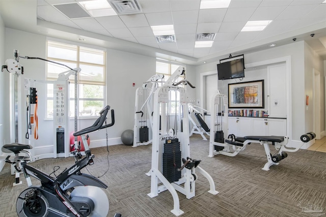 exercise room featuring baseboards, light carpet, and a drop ceiling
