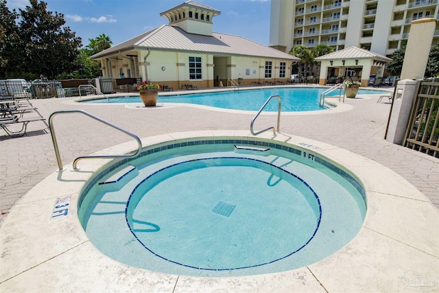 community pool with a community hot tub, fence, and a patio