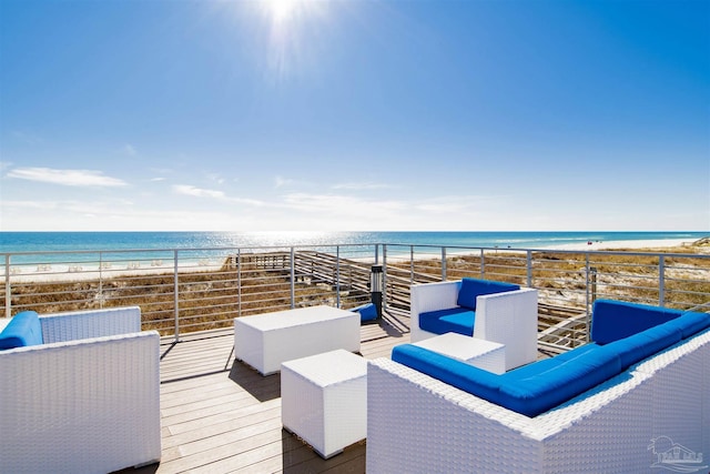 wooden deck with view of water and beach and an outdoor hangout area