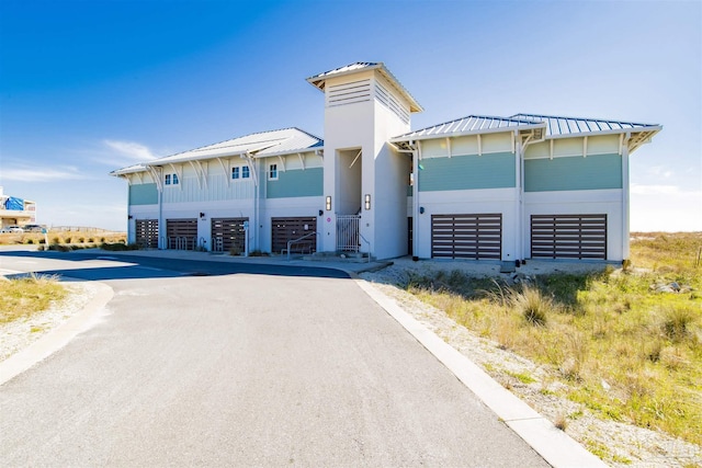 view of front of property featuring a standing seam roof, an attached garage, metal roof, and driveway