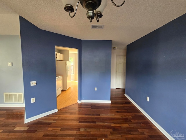 unfurnished bedroom featuring white fridge, dark hardwood / wood-style flooring, and a textured ceiling