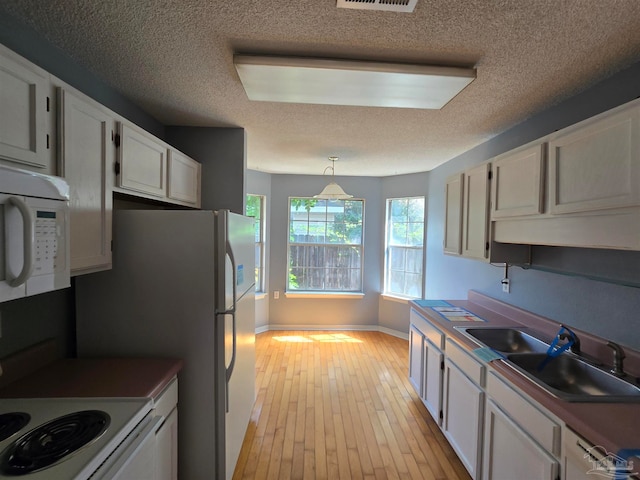 kitchen featuring white cabinets, white appliances, light hardwood / wood-style flooring, and hanging light fixtures