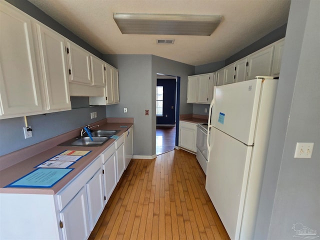 kitchen featuring white cabinetry, sink, light wood-type flooring, and white refrigerator