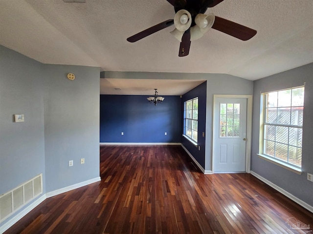 empty room featuring a wealth of natural light, dark wood-type flooring, lofted ceiling, and a textured ceiling