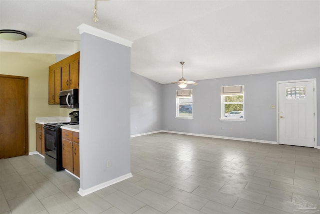 kitchen featuring brown cabinetry, stainless steel microwave, open floor plan, black range with electric stovetop, and light countertops