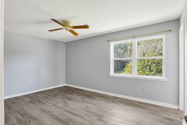 spare room featuring a textured ceiling, dark wood-style flooring, a ceiling fan, and baseboards