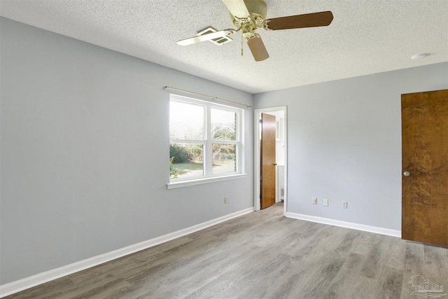 unfurnished bedroom with connected bathroom, ceiling fan, a textured ceiling, wood finished floors, and baseboards