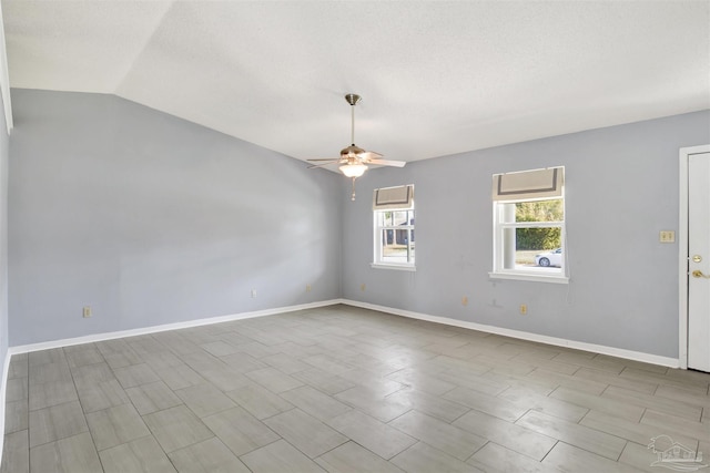 empty room with lofted ceiling, ceiling fan, a textured ceiling, and baseboards