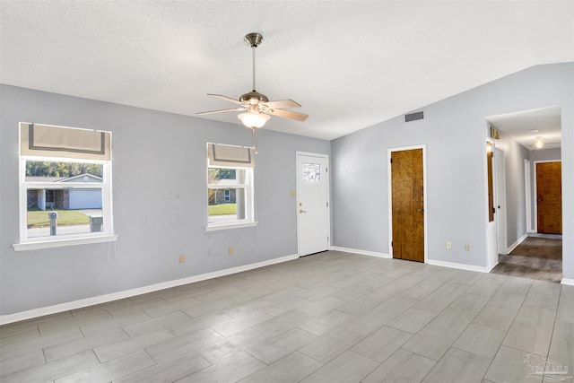 unfurnished room with lofted ceiling, visible vents, light wood-style flooring, a ceiling fan, and baseboards