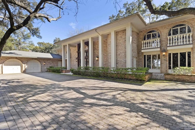 721 W Miracle Strip Pkwy, Mary Esther, FL 32569 - neoclassical home with brick siding, a balcony, decorative driveway, and a garage