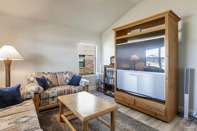 living area featuring baseboards, a healthy amount of sunlight, wood finished floors, and vaulted ceiling