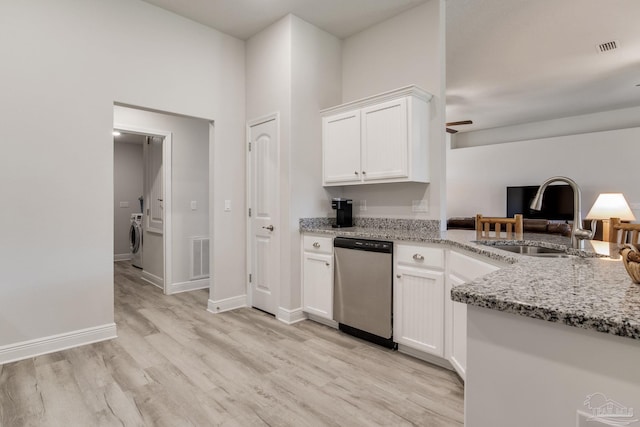 kitchen with light stone countertops, washer / dryer, a sink, stainless steel dishwasher, and light wood-type flooring