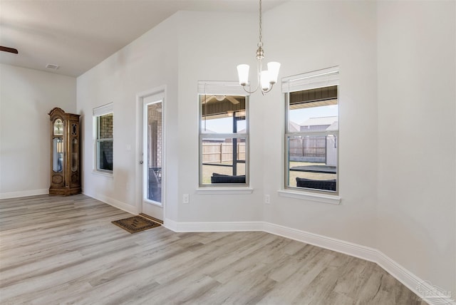 unfurnished room featuring a chandelier, visible vents, baseboards, and wood finished floors