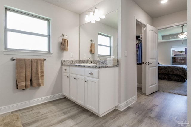 ensuite bathroom featuring connected bathroom, baseboards, wood finished floors, and vanity