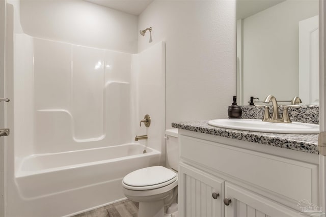 bathroom with vanity, toilet, wood finished floors, and  shower combination