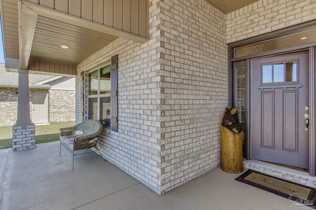 entrance to property featuring a porch and brick siding