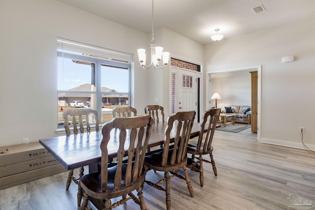 dining area featuring a chandelier, visible vents, light wood finished floors, and baseboards