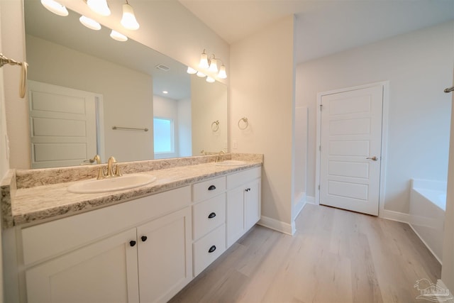 bathroom featuring a bath, wood-type flooring, and vanity