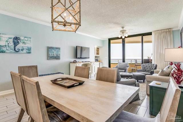 dining space with expansive windows, crown molding, ceiling fan with notable chandelier, and a textured ceiling