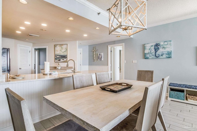 dining room featuring a textured ceiling, ornamental molding, and sink