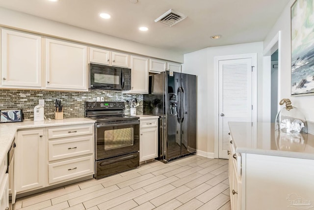 kitchen with black appliances, light hardwood / wood-style floors, white cabinetry, and backsplash