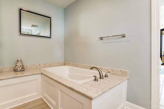 bathroom with wood-type flooring and a bath