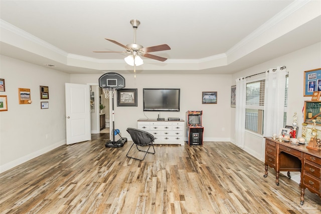 living area featuring crown molding, a raised ceiling, ceiling fan, wood finished floors, and baseboards