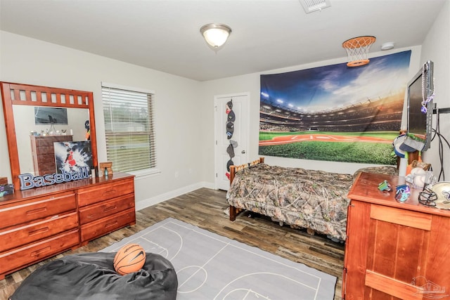 bedroom with baseboards, visible vents, and wood finished floors