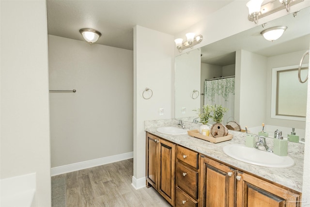 bathroom featuring double vanity, a sink, baseboards, and wood finished floors