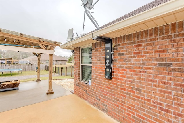 view of patio with a trampoline and fence