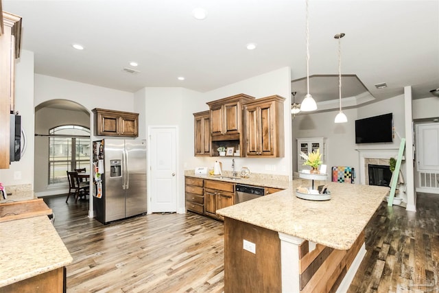 kitchen featuring a peninsula, appliances with stainless steel finishes, wood finished floors, and a tile fireplace