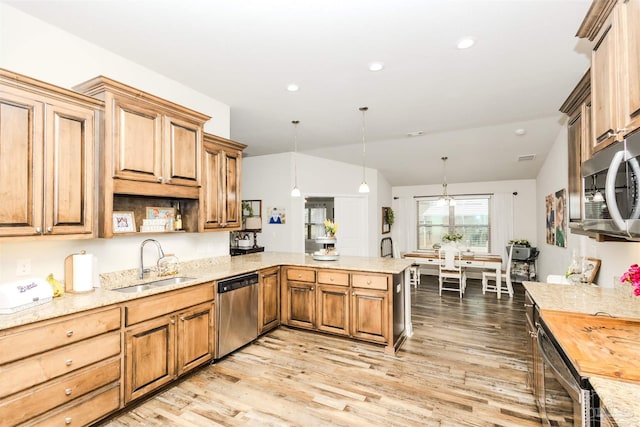 kitchen with stainless steel appliances, a peninsula, a sink, light wood-type flooring, and decorative light fixtures