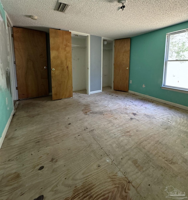 unfurnished bedroom featuring two closets and a textured ceiling