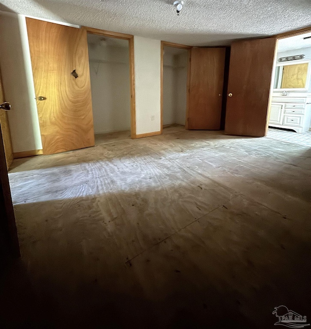 unfurnished bedroom featuring multiple closets and a textured ceiling