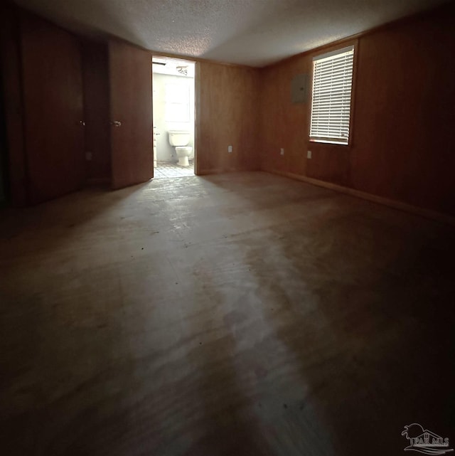 empty room with concrete floors, a textured ceiling, and wooden walls