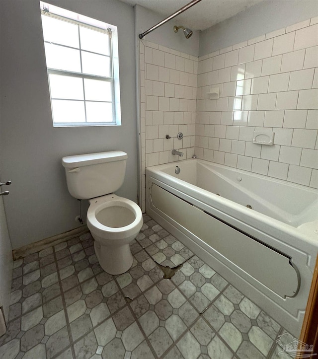 bathroom featuring toilet and tiled shower / bath