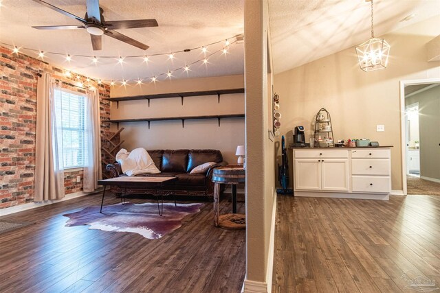 living room with hardwood / wood-style floors, ceiling fan with notable chandelier, a textured ceiling, and brick wall