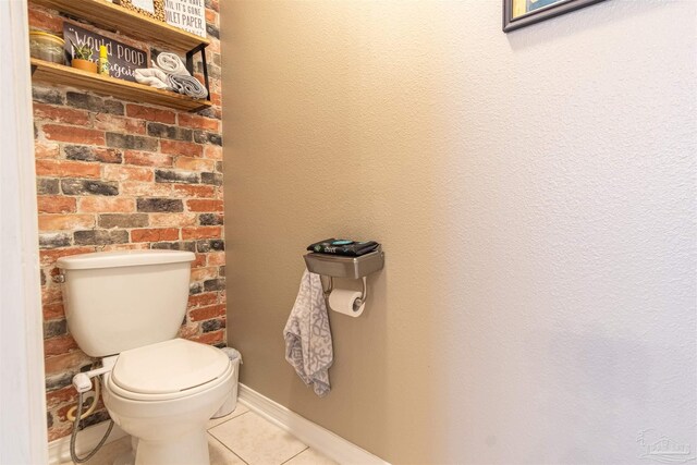 bathroom featuring brick wall, toilet, and tile patterned floors