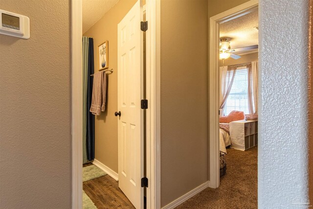 corridor featuring dark hardwood / wood-style flooring and a textured ceiling