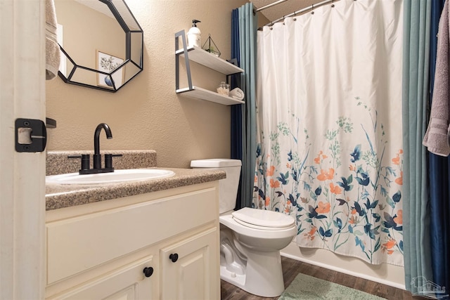 bathroom featuring a textured wall, toilet, wood finished floors, vanity, and shower / bath combo with shower curtain