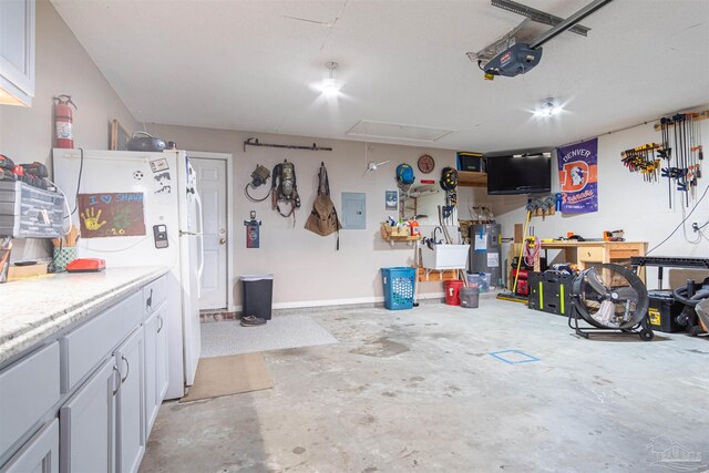 garage featuring electric panel, white fridge, a garage door opener, and water heater