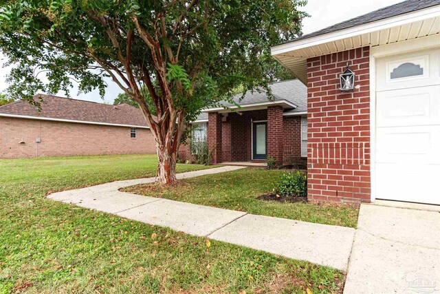 view of exterior entry featuring a yard and a garage