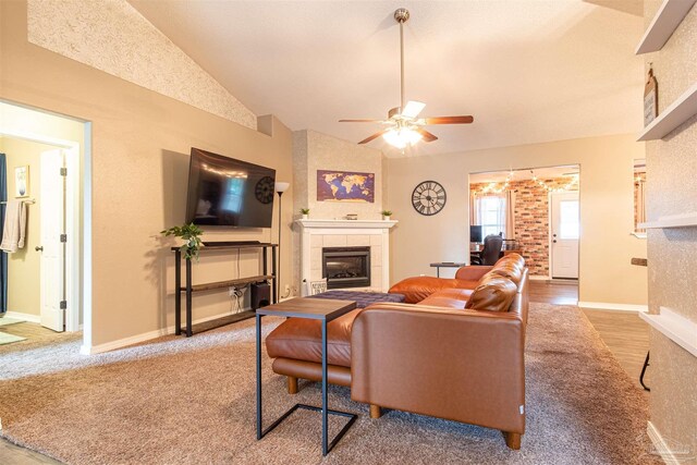 living room featuring ceiling fan, hardwood / wood-style flooring, a fireplace, and vaulted ceiling