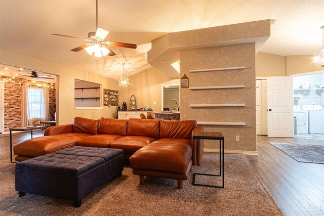 living room featuring ceiling fan with notable chandelier, independent washer and dryer, wood-type flooring, and vaulted ceiling