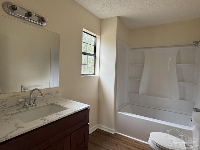 full bathroom with washtub / shower combination, toilet, wood-type flooring, a textured ceiling, and vanity