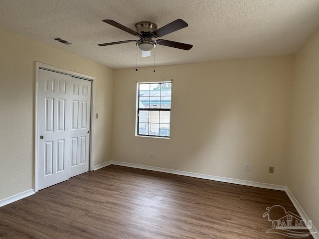 unfurnished bedroom with dark wood-type flooring, ceiling fan, a closet, and a textured ceiling