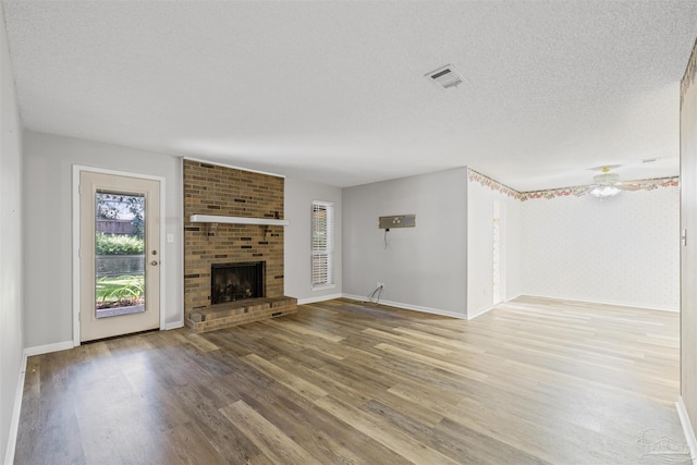 4831 E Olive Rd Unit 2A, Pensacola, FL 32514 - unfurnished living room with wood finished floors, a fireplace, baseboards, and a textured ceiling