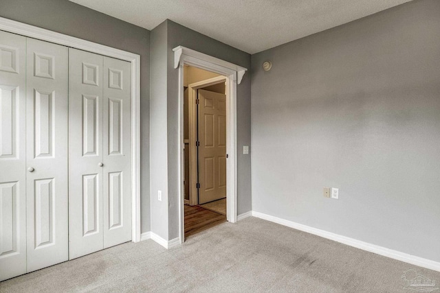 unfurnished bedroom with light carpet, a closet, and a textured ceiling