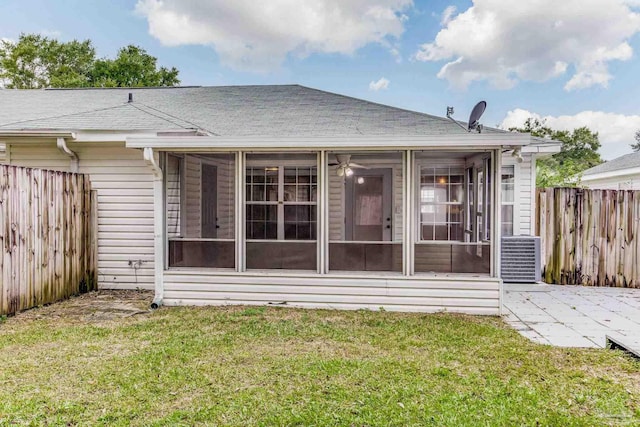 back of property featuring a sunroom, a lawn, and central AC