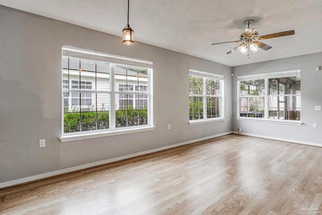 unfurnished room featuring a textured ceiling, light hardwood / wood-style flooring, plenty of natural light, and ceiling fan